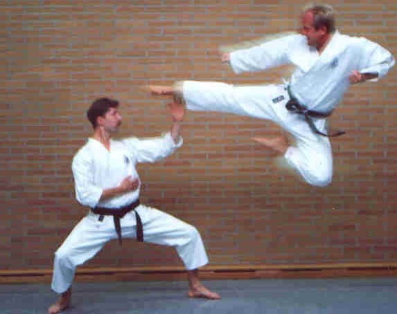 Gestellte Szene: Zwei Karate Kampfkünstler, einer greift mit einem gesprungenem Fußtritt (Mae tobi-geri) an, der andere verteidigt.